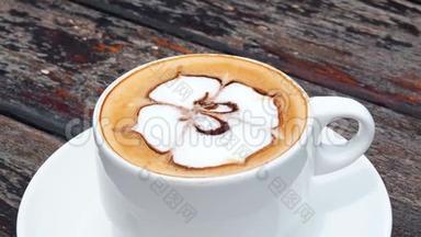 风味咖啡在白色的杯子里放在盘子里，用勺子放在木制的乡村桌子上，波浪运动。 喝着海景咖啡